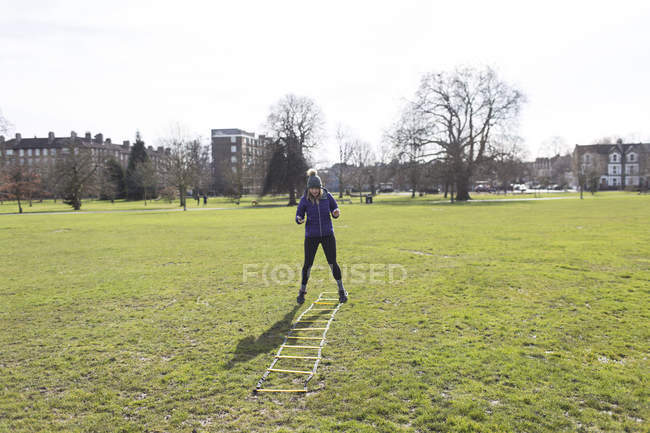 Frau übt, macht Speedleiter-Übung im sonnigen Park — Stockfoto