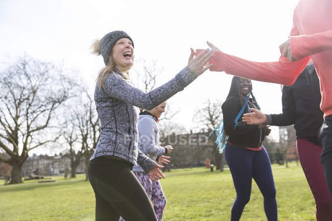 Enthusiastic woman high-fiving classmate, exercising in sunny park — Stock Photo