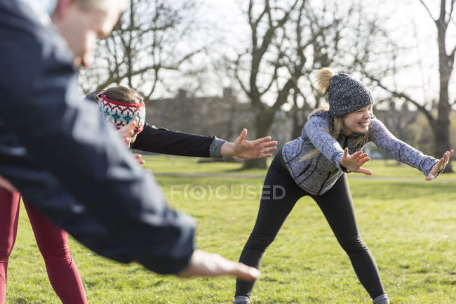 Smiling woman stretching, exercising in park — Stock Photo