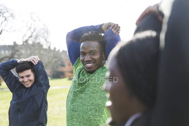 Portrait smiling, confident man stretching, exercising in park — Stock Photo