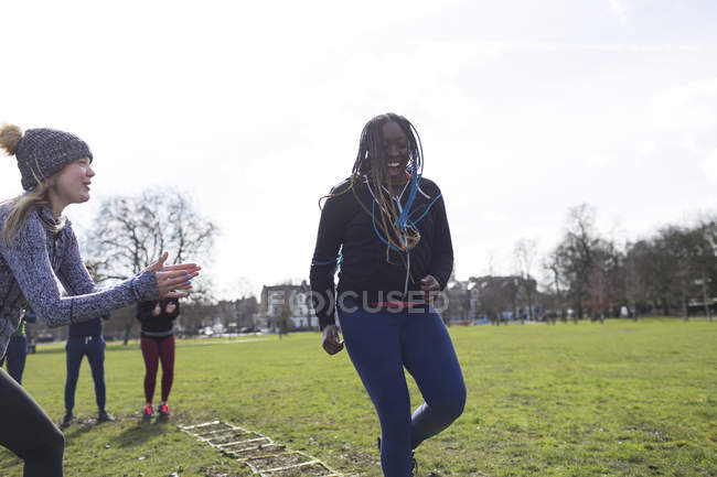 Smiling woman doing speed ladder drill in sunny park — Stock Photo