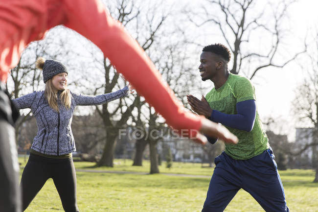 Люди займаються спортом, розтягуються в зеленому парку — стокове фото