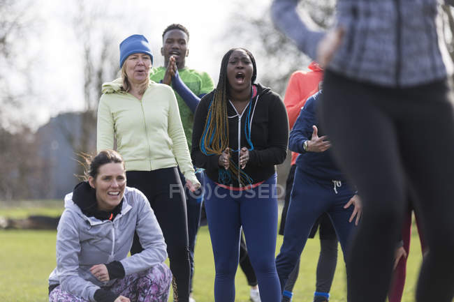 Team jubelt Frau beim Training im Park zu — Stockfoto