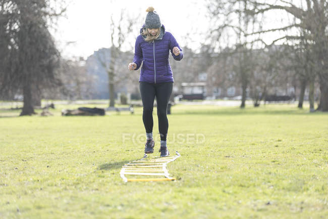 Femme faisant des exercices d'échelle de vitesse dans un parc ensoleillé — Photo de stock