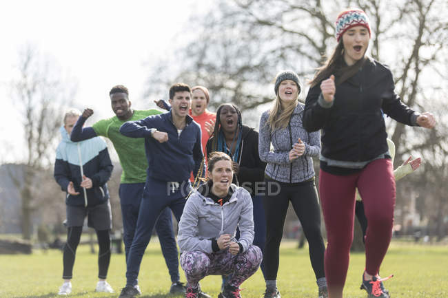 Team jubelt Frau beim Laufen im sonnigen Park zu — Stockfoto