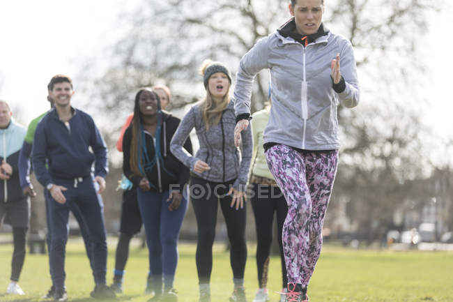 Team cheering woman running in sunny park — Stock Photo