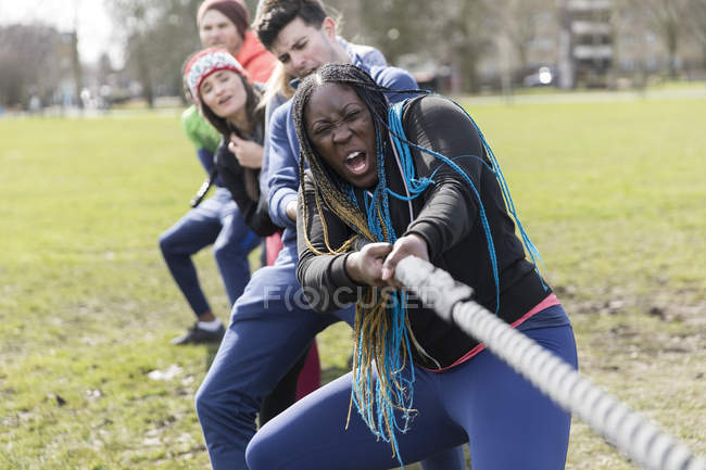 Determined team pulling rope in tug-of-war at park — Stock Photo