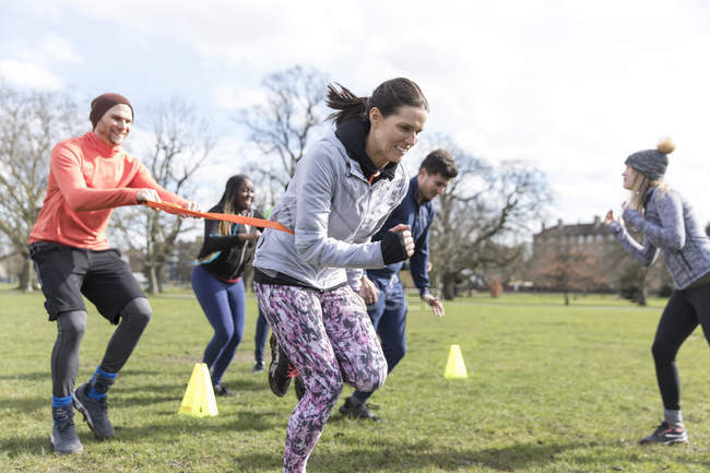 Люди бегают, участвуют в командных упражнениях в солнечном парке — стоковое фото