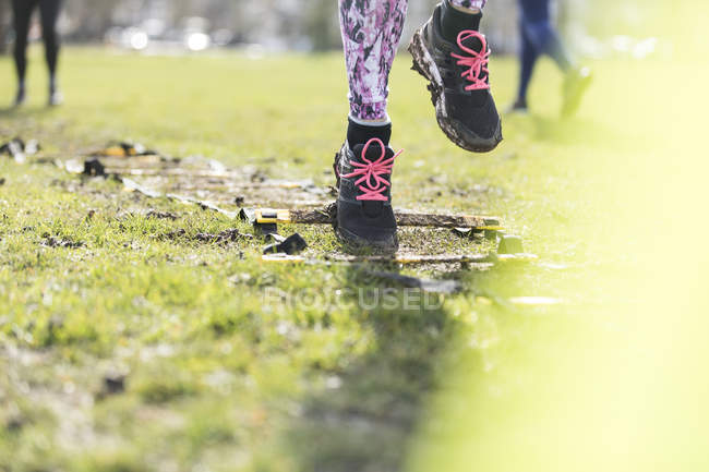 Cropped image of woman doing speed ladder drill in sunny park — Stock Photo