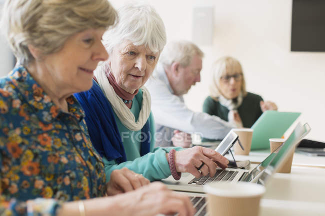 Femmes d'affaires seniors utilisant des ordinateurs portables dans la salle de conférence réunion — Photo de stock
