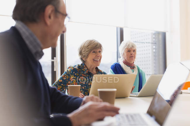 Senior businesswomen using laptops in conference room meeting — Stock Photo