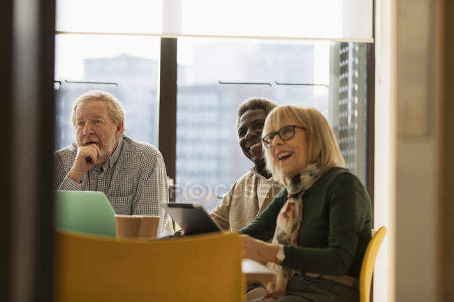 Des hommes d'affaires seniors souriants dans une réunion de salle de conférence — Photo de stock