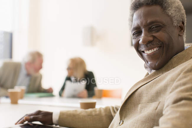 Portrait homme d'affaires senior souriant et confiant dans une réunion de salle de conférence — Photo de stock