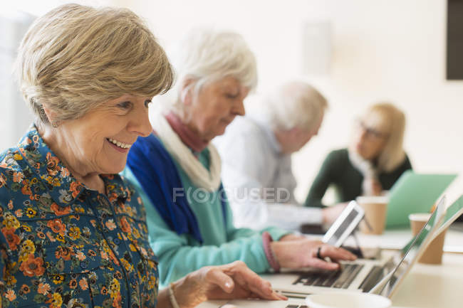 Mujeres mayores que usan computadoras portátiles en la reunión de la sala de conferencias - foto de stock