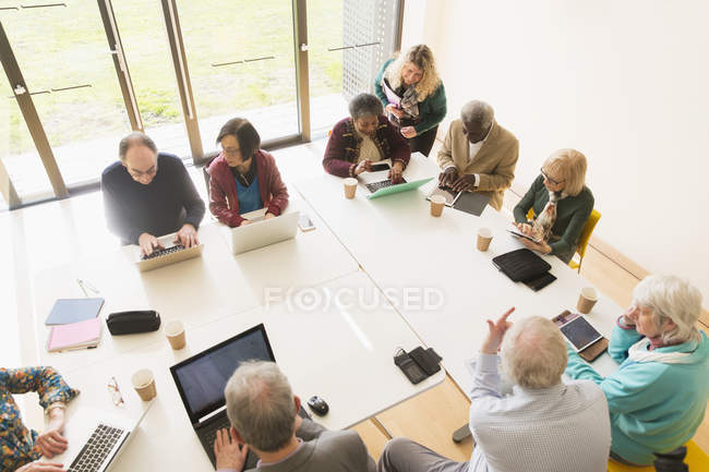 Senior business people using laptops and digital tablets in conference room meeting — Stock Photo