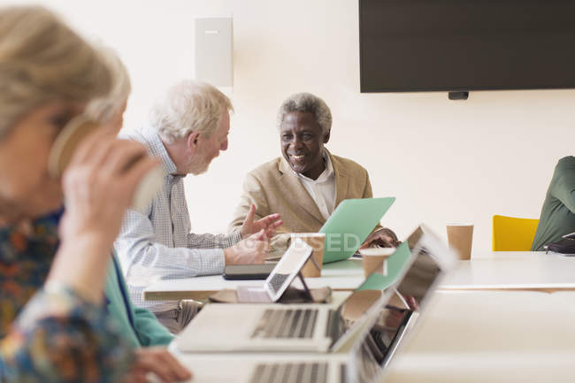 Empresários seniores usando laptop em reunião de sala de conferências — Fotografia de Stock