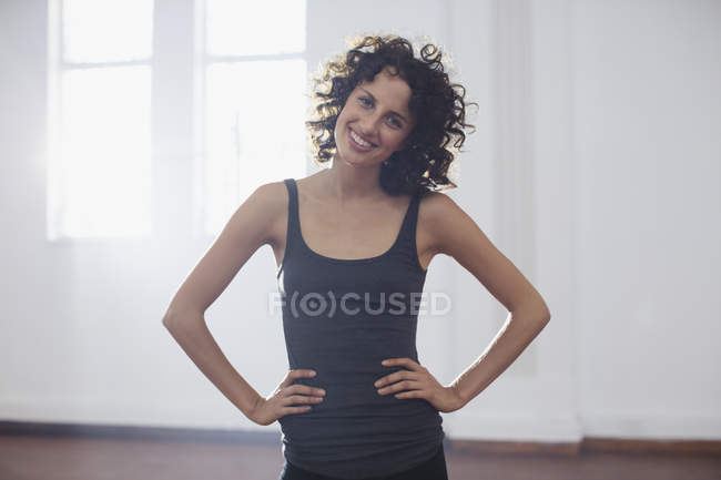 Портрет улыбающейся, уверенной молодой танцовщицы в танцевальной студии — стоковое фото