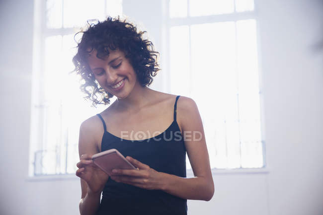 Lächelnde junge Tänzerin beim SMS-Schreiben mit Smartphone im Tanzstudio — Stockfoto