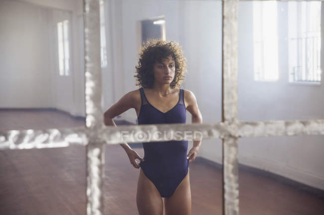 Сосредоточена на молодой танцовщице, стоящей перед зеркалом в танцевальной студии — стоковое фото