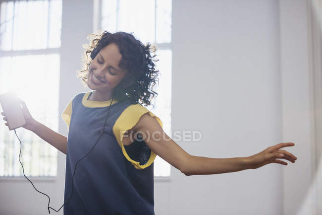 Беззаботная молодая танцовщица слушает музыку в наушниках и mp3 плеере — стоковое фото