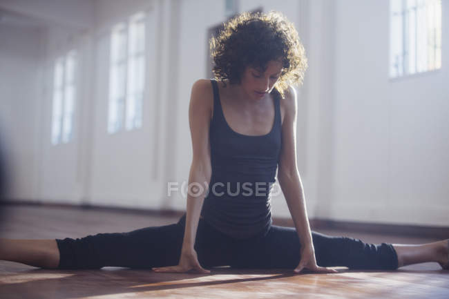 Strong young female dancer stretching, doing the splits in dance studio — Stock Photo