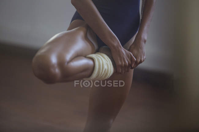 Starke, junge Tänzerin, die Bein streckt — Stockfoto