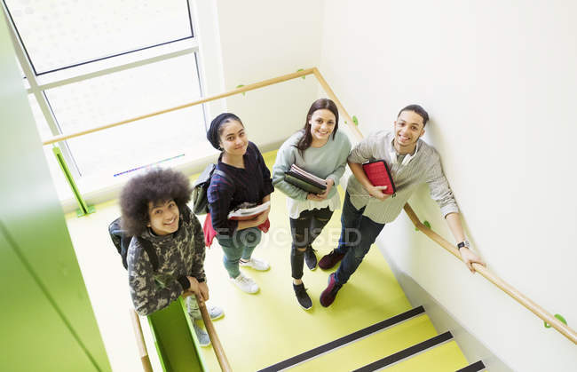 Retrato sonriendo estudiantes de secundaria en el rellano de la escalera - foto de stock