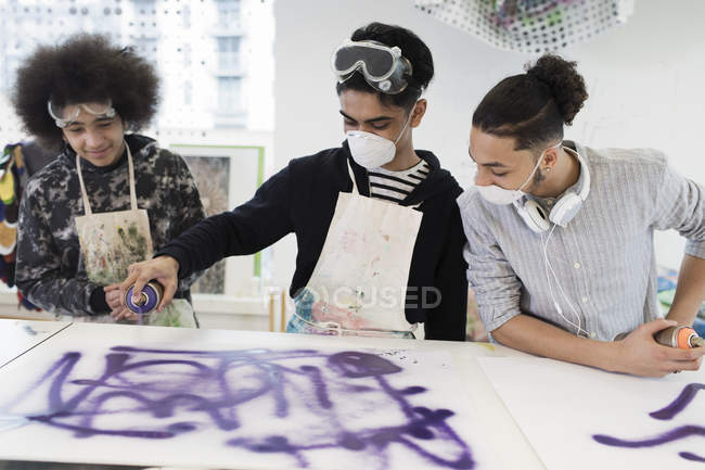 Les garçons adolescents pulvérisent la peinture dans la classe d'art du lycée — Photo de stock