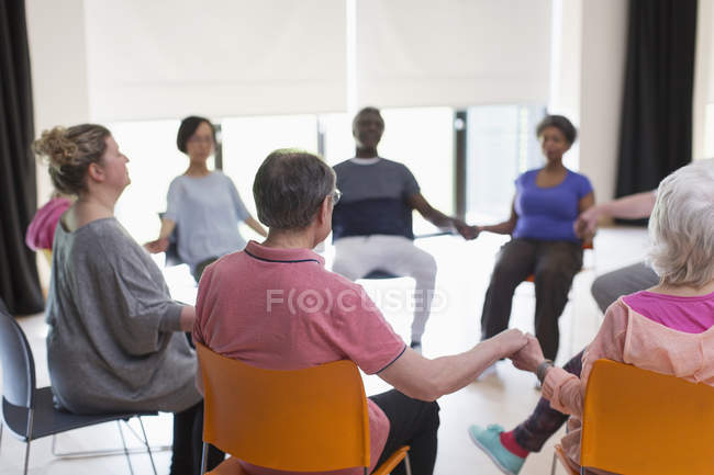 Gelassene aktive Senioren halten Händchen, meditieren im Kreis — Stockfoto