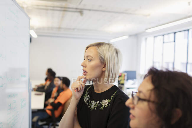 Mulheres de negócios focadas em brainstorming no quadro branco no escritório — Fotografia de Stock