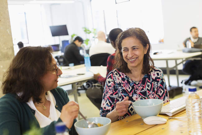 Happy businesswomen eating lunch in office — Stock Photo