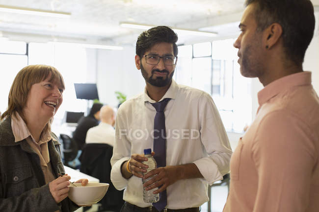 Geschäftsleute reden und essen im Büro — Stockfoto