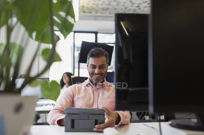 Усміхнений бізнесмен використовує цифровий планшет в офісі — стокове фото