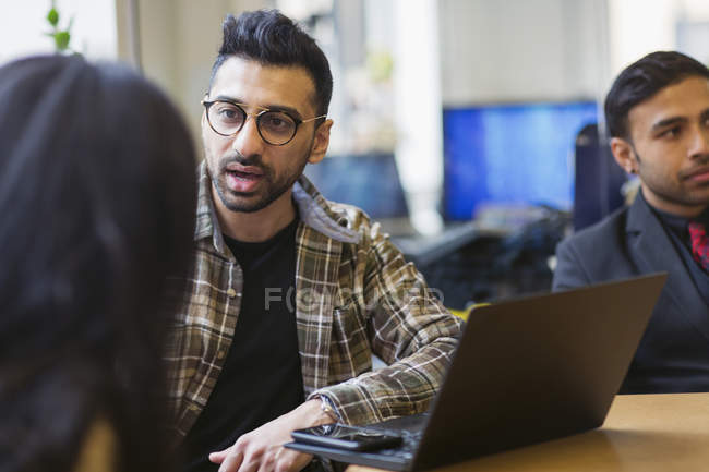 Businessman at laptop talking with colleague — Stock Photo