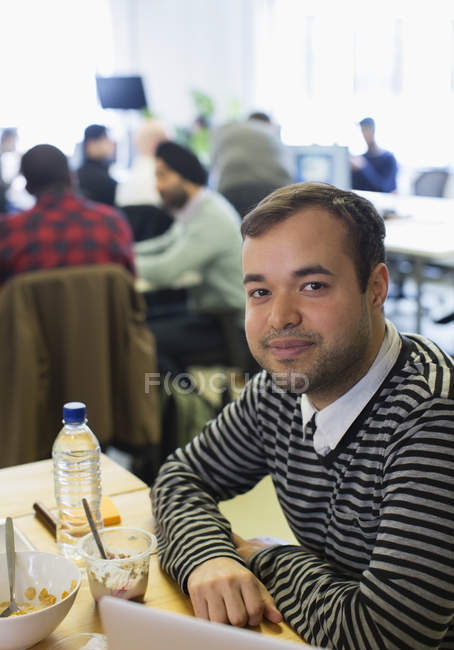 Portrait confident businessman eating breakfast in office — Stock Photo