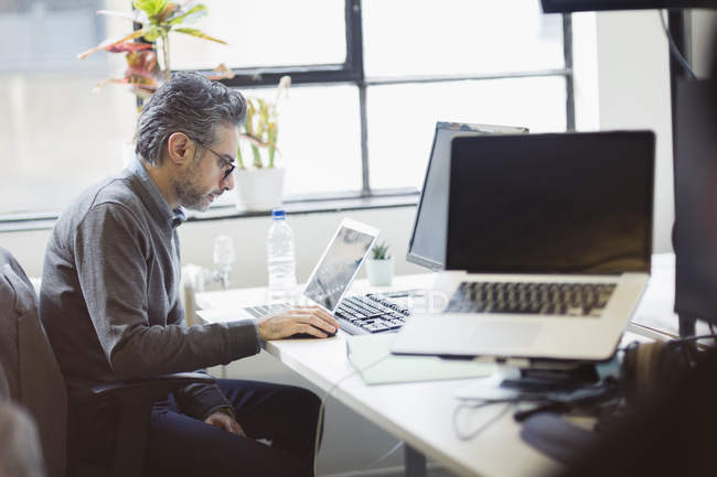 Сфокусированный бизнесмен, работающий за ноутбуком в офисе — стоковое фото