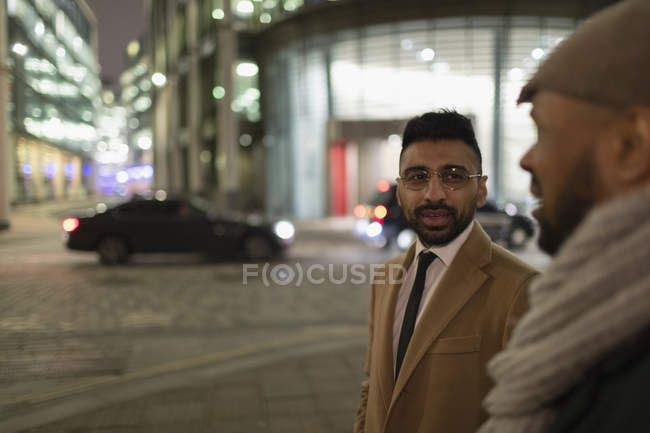 Empresarios hablando en la calle de la ciudad por la noche - foto de stock