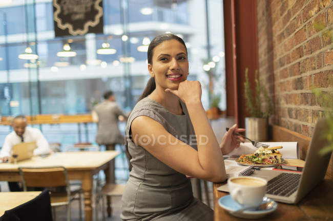 Confident businesswoman eating lunch and working in cafe — Stock Photo
