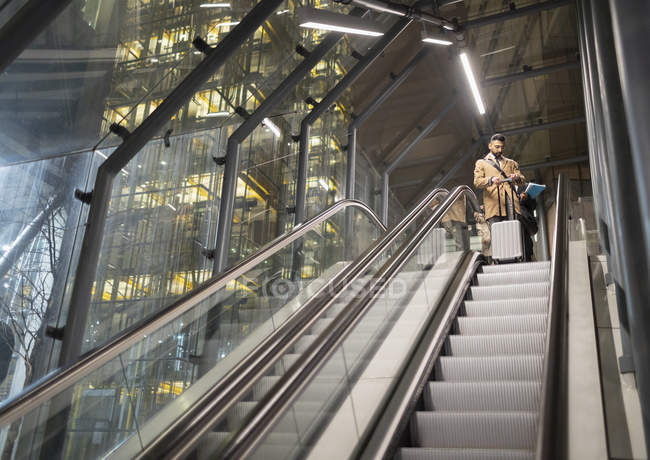 Homme d'affaires avec valise sur escalator urbain — Photo de stock