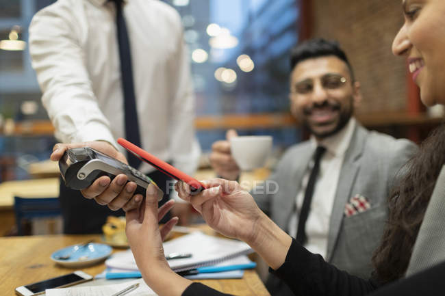 Businesswoman paying with smart phone contactless payment in cafe — Stock Photo