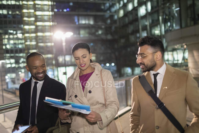 Empresários caminhando e discussão papelada na cidade à noite — Fotografia de Stock
