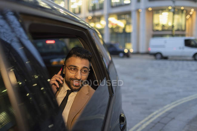 Businessman talking on smart phone in crowdsourced taxi — Stock Photo