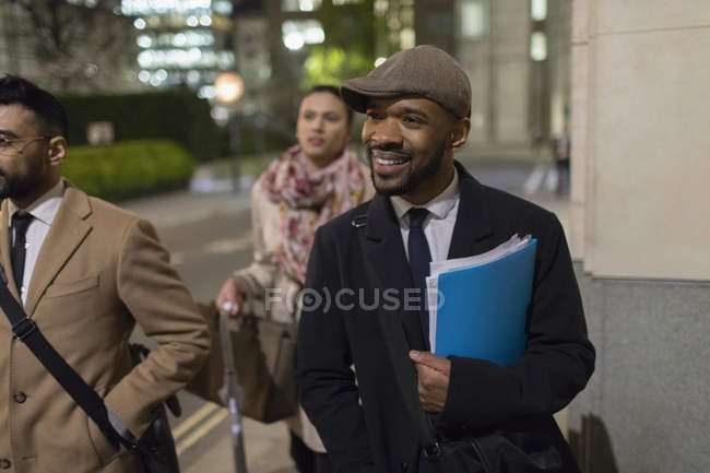 Empresário sorridente andando na calçada urbana à noite — Fotografia de Stock