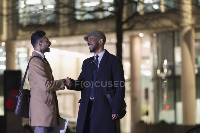 Businessmen handshaking on urban street at night — Stock Photo