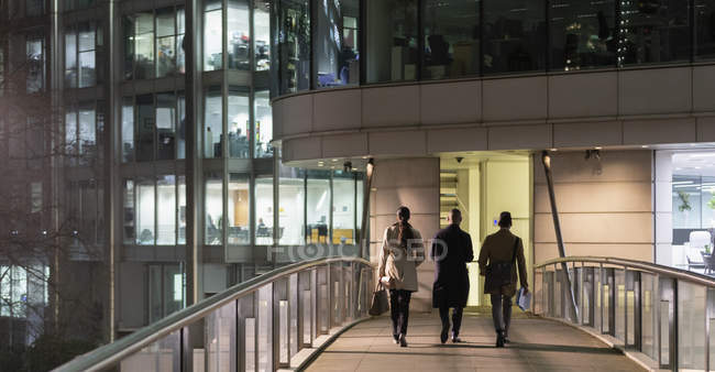 Business people walking on urban pedestrian bridge at night — Stock Photo
