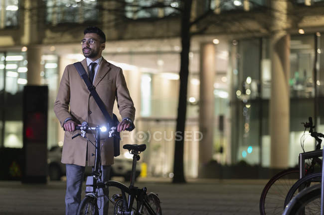 Businessman with bicycle on urban street at night — Stock Photo