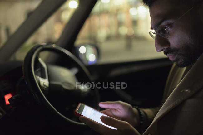 Man using smart phone in car at night — Stock Photo