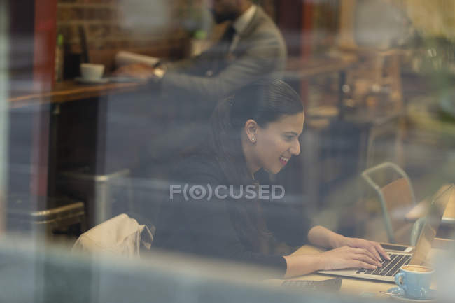 Smiling businesswoman working at laptop in cafe — Stock Photo