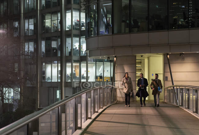 Business people walking on urban pedestrian bridge at night — Stock Photo