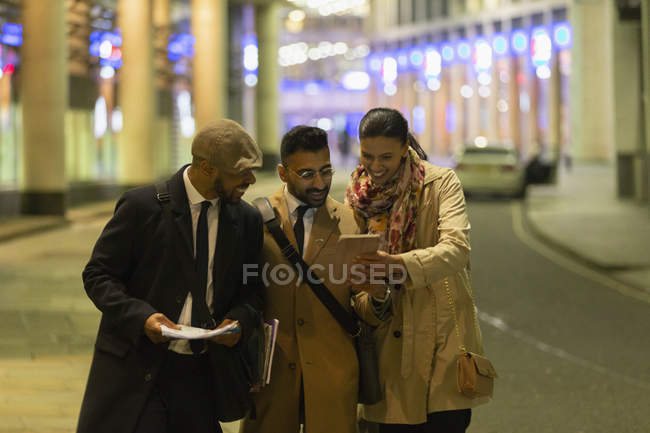 Empresários usando tablet digital na rua urbana à noite — Fotografia de Stock
